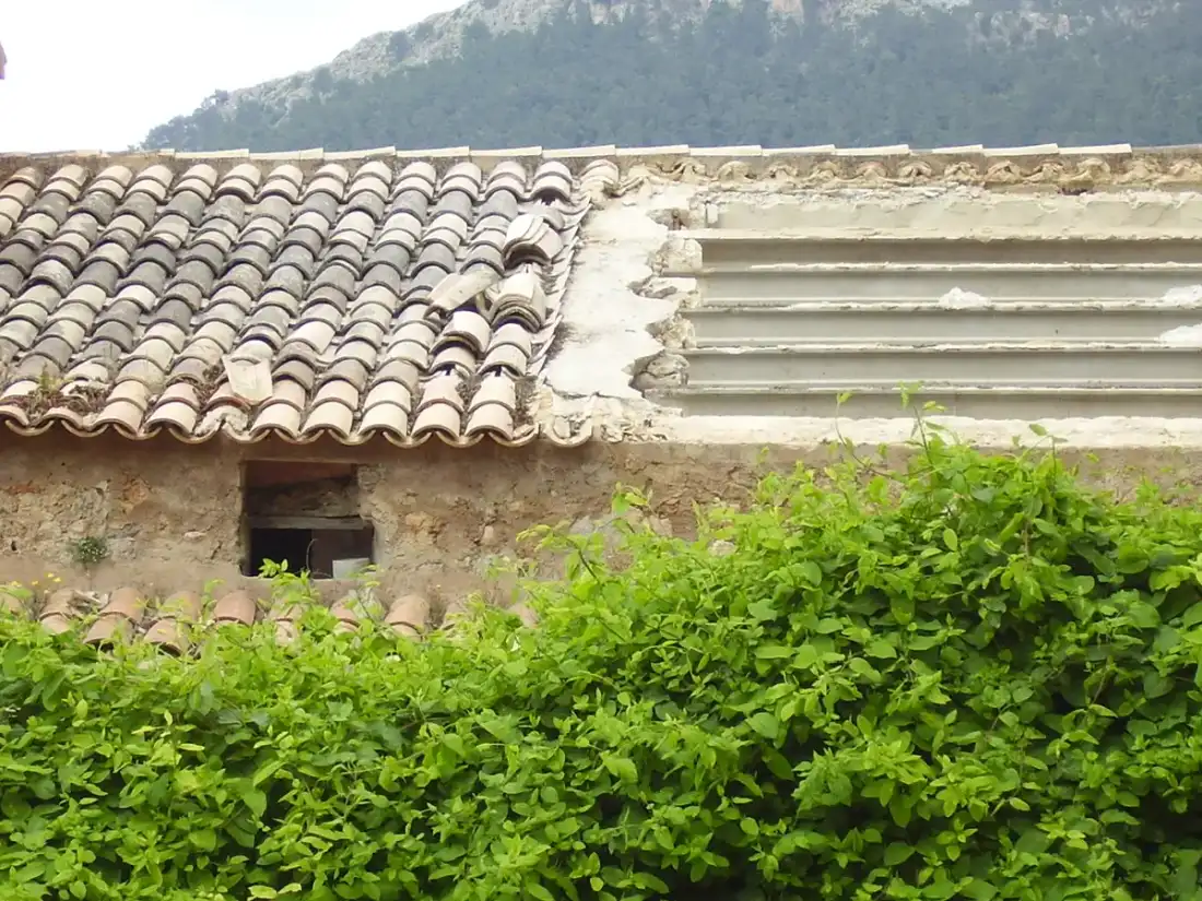 Tejado de teja árabe envejecido sobre un muro de piedra